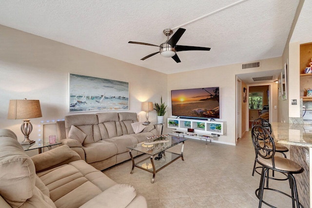 living room featuring a textured ceiling, light tile patterned floors, and ceiling fan