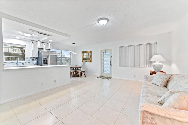 unfurnished living room featuring a textured ceiling, light tile patterned flooring, and sink