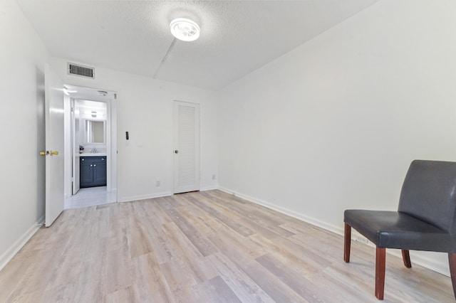 living area featuring sink, light wood-type flooring, and a textured ceiling