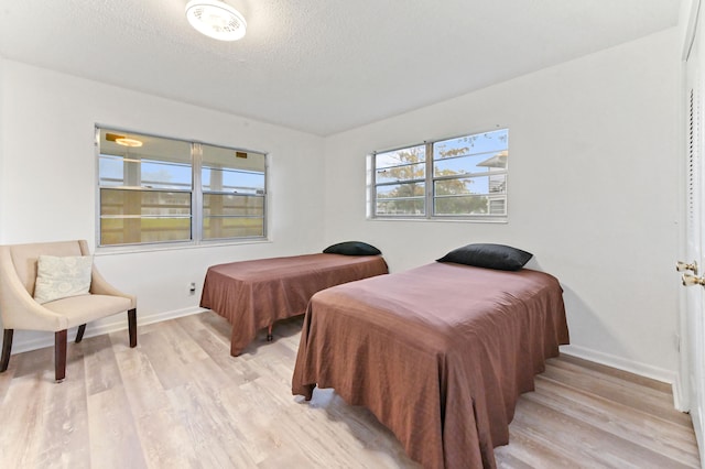 bedroom with a textured ceiling and light hardwood / wood-style flooring