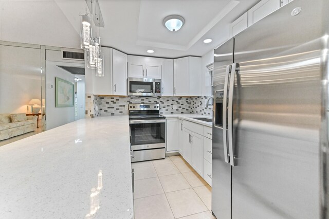 kitchen with stainless steel appliances, white cabinets, and decorative light fixtures