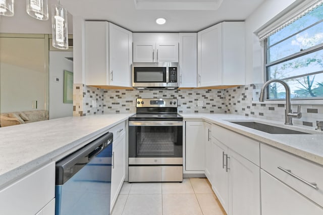 kitchen featuring white cabinetry, appliances with stainless steel finishes, sink, and decorative light fixtures