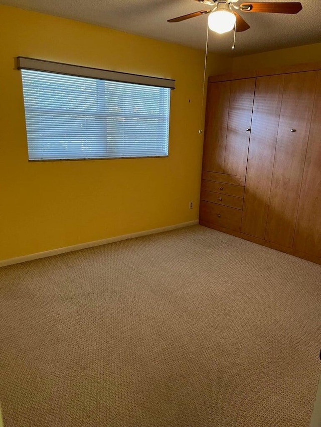 unfurnished bedroom with ceiling fan, a textured ceiling, and carpet