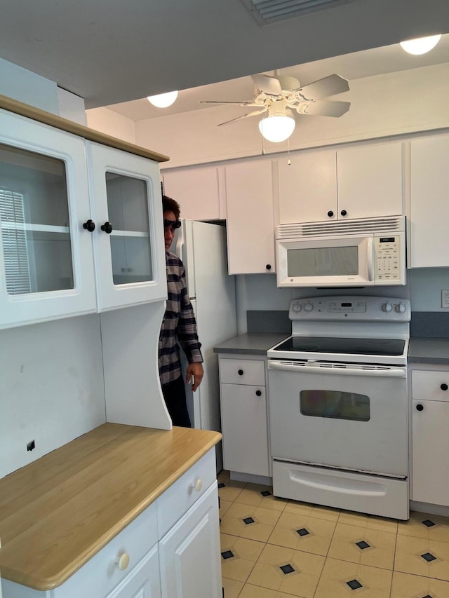 kitchen with white appliances, light tile patterned floors, ceiling fan, and white cabinets