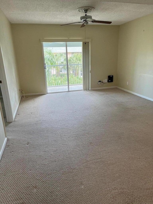 empty room with ceiling fan, light colored carpet, and a textured ceiling