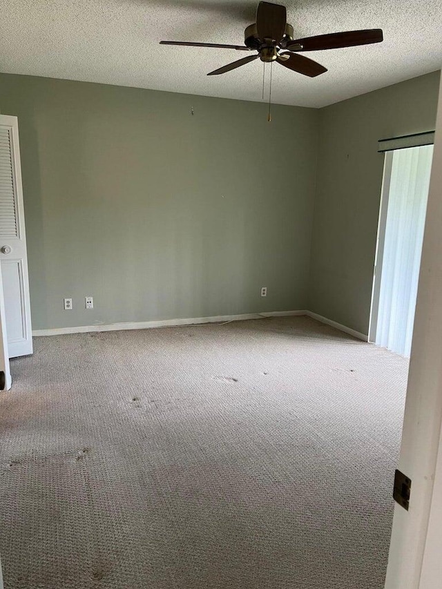 spare room featuring light carpet, a textured ceiling, and ceiling fan