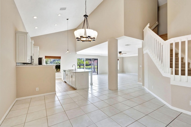 kitchen with high vaulted ceiling, ceiling fan with notable chandelier, sink, an island with sink, and decorative light fixtures