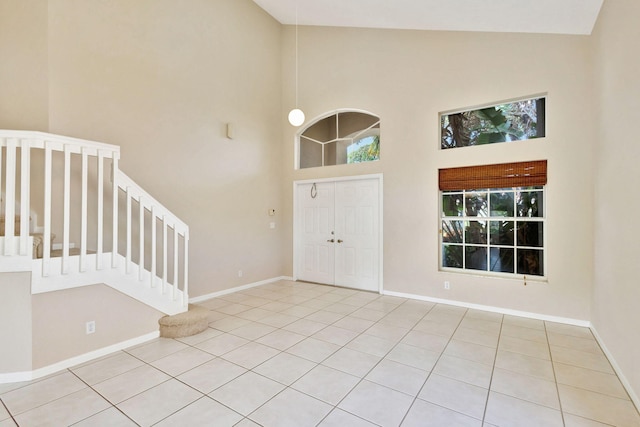 foyer with high vaulted ceiling and light tile patterned flooring