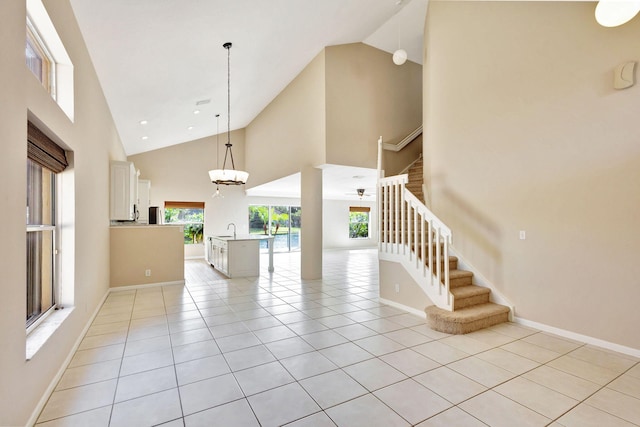 unfurnished living room featuring sink, high vaulted ceiling, and light tile patterned floors