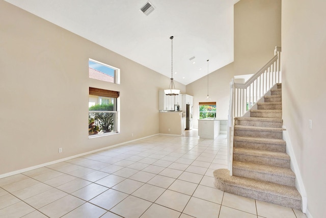 staircase featuring tile patterned floors and high vaulted ceiling