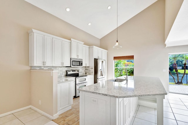 kitchen featuring white cabinetry, sink, light stone counters, pendant lighting, and appliances with stainless steel finishes