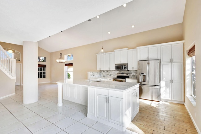 kitchen with white cabinets, sink, stainless steel appliances, and a center island with sink