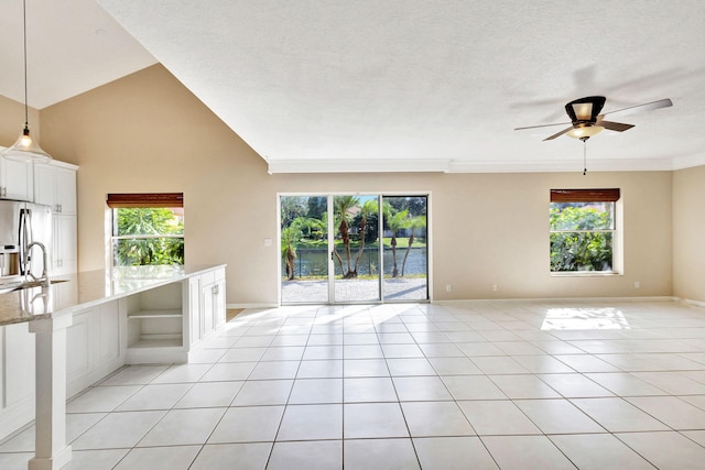 unfurnished living room featuring sink, a textured ceiling, ceiling fan, and light tile patterned flooring