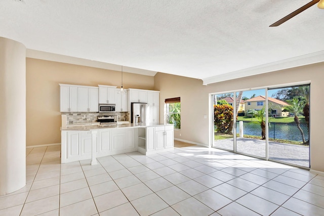 kitchen with a water view, white cabinetry, stainless steel appliances, and a wealth of natural light