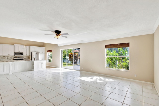 unfurnished living room featuring ceiling fan, light tile patterned flooring, ornamental molding, and a textured ceiling