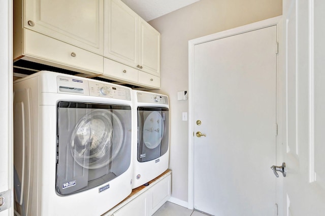 clothes washing area featuring cabinets and washing machine and clothes dryer