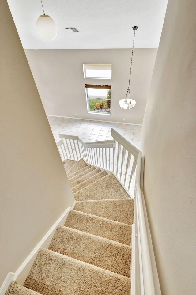 stairway featuring a chandelier and tile patterned floors