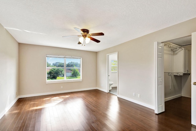 unfurnished bedroom with ceiling fan, a textured ceiling, connected bathroom, dark hardwood / wood-style flooring, and a closet