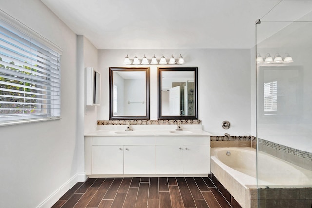 bathroom with tiled bath, vanity, and wood-type flooring