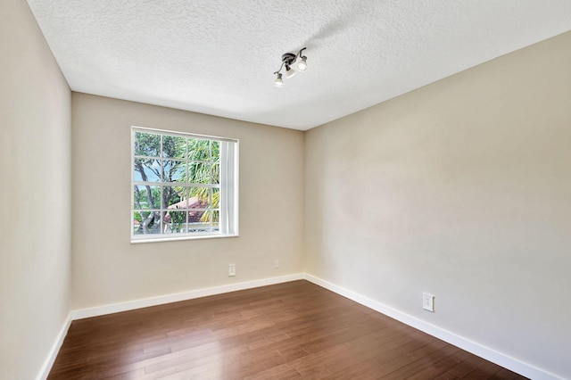 empty room featuring a textured ceiling and dark hardwood / wood-style floors