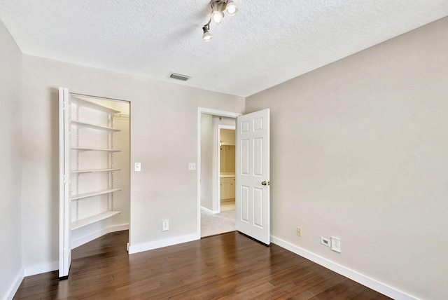 unfurnished bedroom with a textured ceiling, dark hardwood / wood-style floors, and a closet