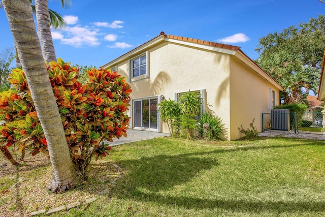 rear view of property featuring central AC unit and a lawn