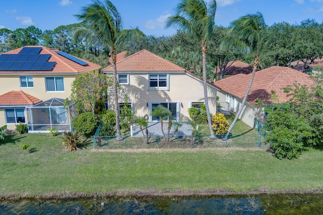 rear view of property featuring a yard, a water view, and a lanai