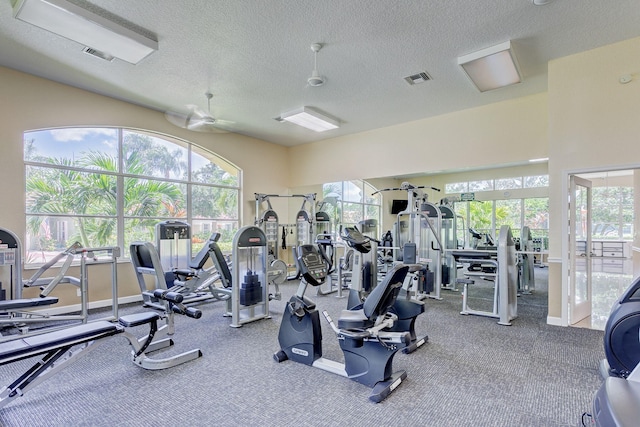 gym with ceiling fan, carpet, and a textured ceiling