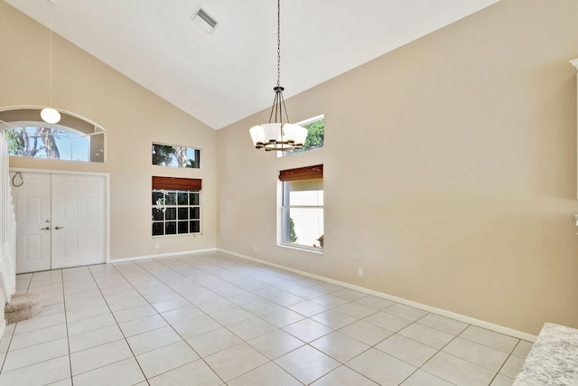 foyer entrance featuring light tile patterned floors, high vaulted ceiling, and an inviting chandelier