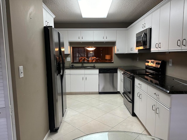 kitchen featuring a textured ceiling, sink, light tile patterned floors, white cabinetry, and appliances with stainless steel finishes