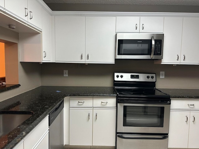 kitchen with dark stone counters, white cabinetry, appliances with stainless steel finishes, and a textured ceiling