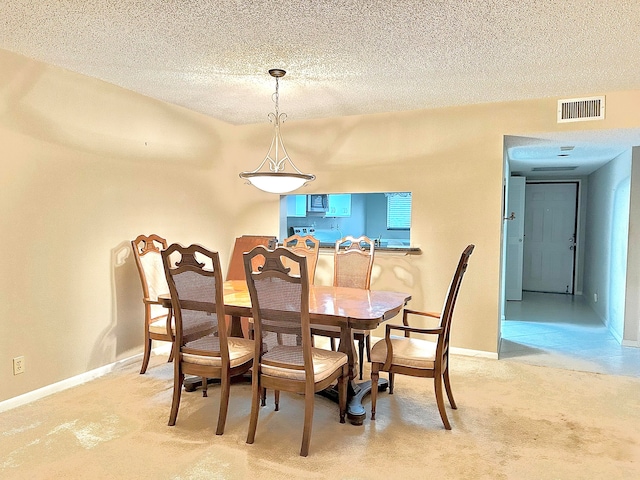 carpeted dining room with a textured ceiling