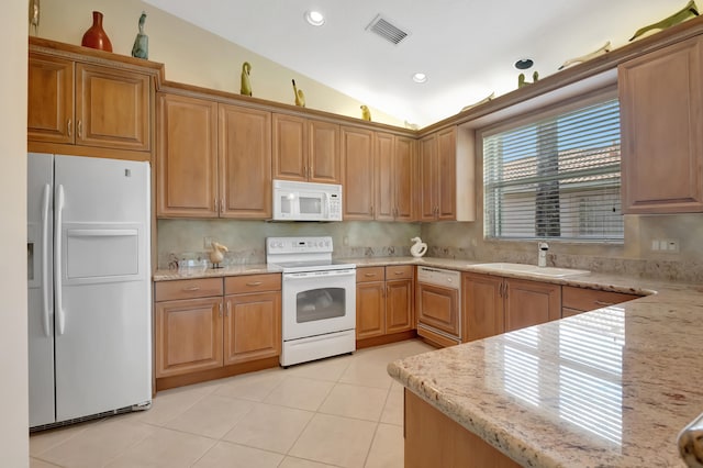 kitchen with light stone countertops, sink, lofted ceiling, white appliances, and light tile patterned floors