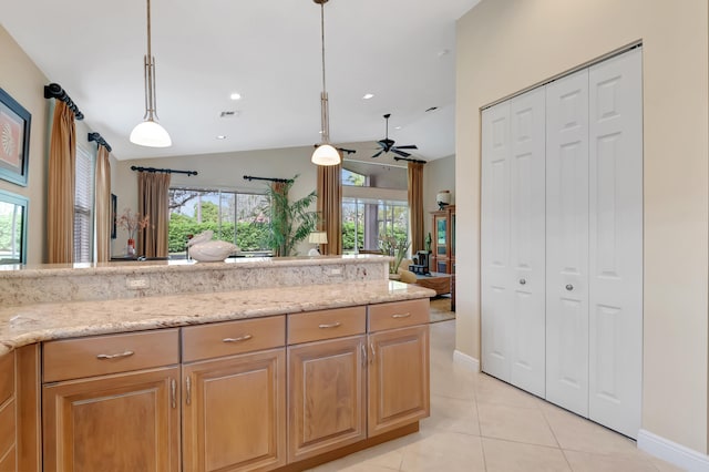 kitchen with light stone countertops, vaulted ceiling, ceiling fan, light tile patterned floors, and decorative light fixtures