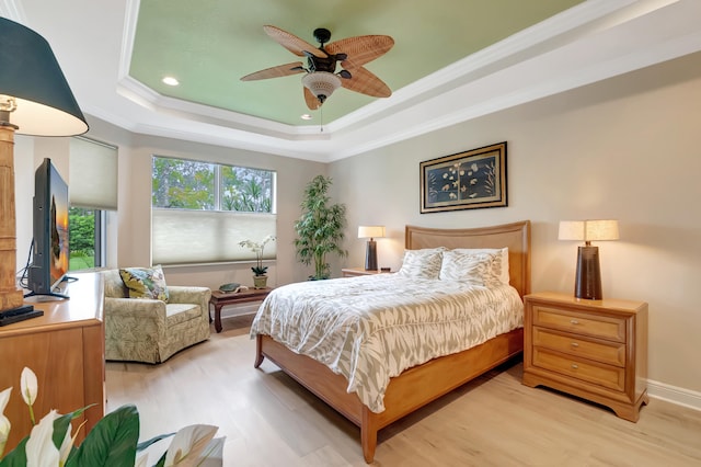 bedroom with a raised ceiling, ceiling fan, light hardwood / wood-style floors, and ornamental molding