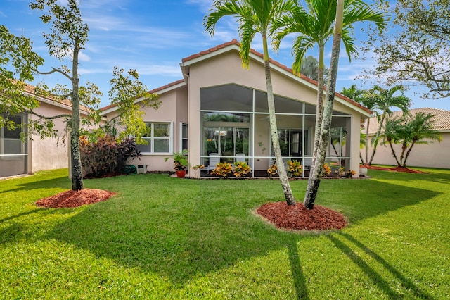 back of property featuring a sunroom and a lawn