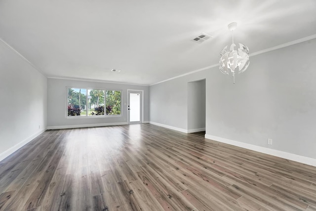 empty room featuring an inviting chandelier, dark hardwood / wood-style floors, and crown molding