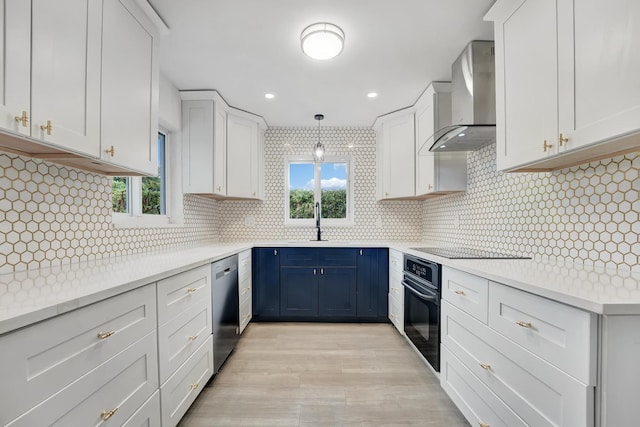 kitchen featuring decorative backsplash, wall chimney exhaust hood, hanging light fixtures, black appliances, and white cabinetry