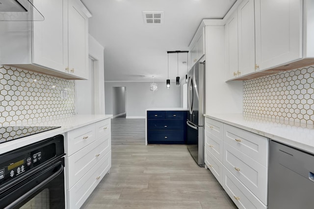 kitchen with stainless steel appliances, white cabinets, light hardwood / wood-style flooring, and decorative backsplash