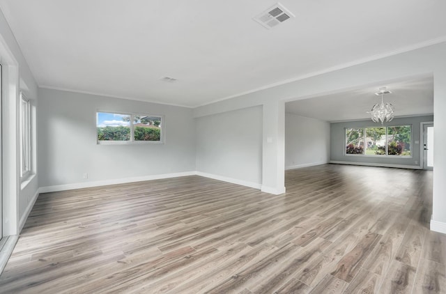 unfurnished living room with light hardwood / wood-style floors, plenty of natural light, and a notable chandelier