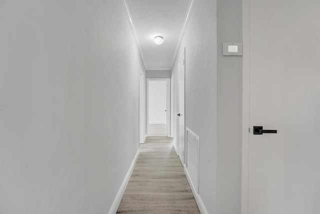 corridor with light wood-type flooring and crown molding