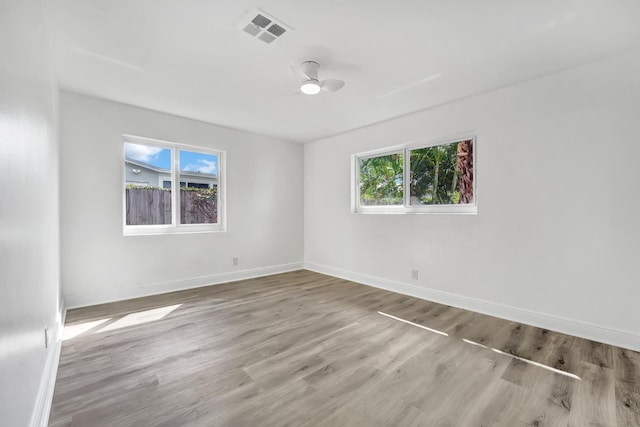 empty room featuring light wood-type flooring, a wealth of natural light, and ceiling fan