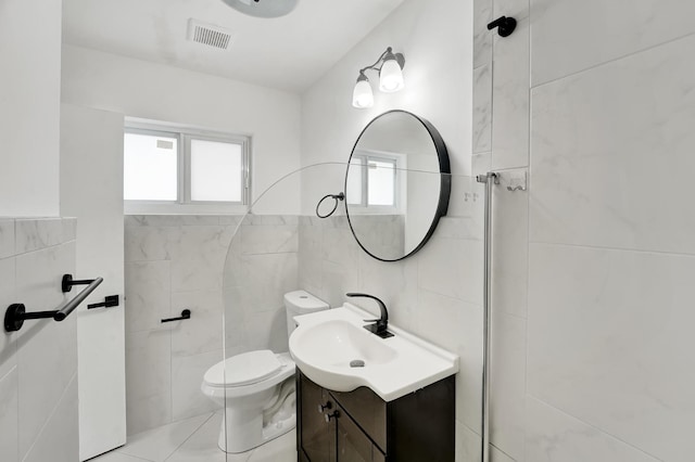 bathroom with tile walls, tile patterned flooring, vanity, and toilet