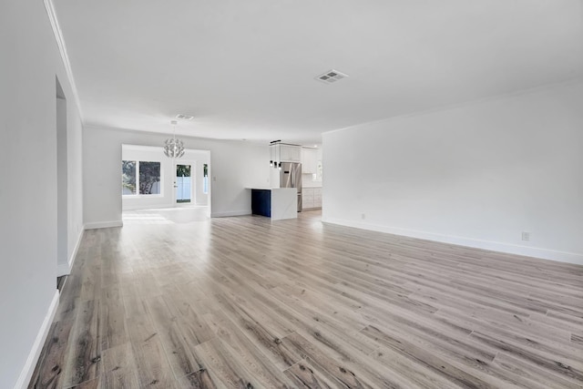 unfurnished living room featuring light wood-type flooring and an inviting chandelier