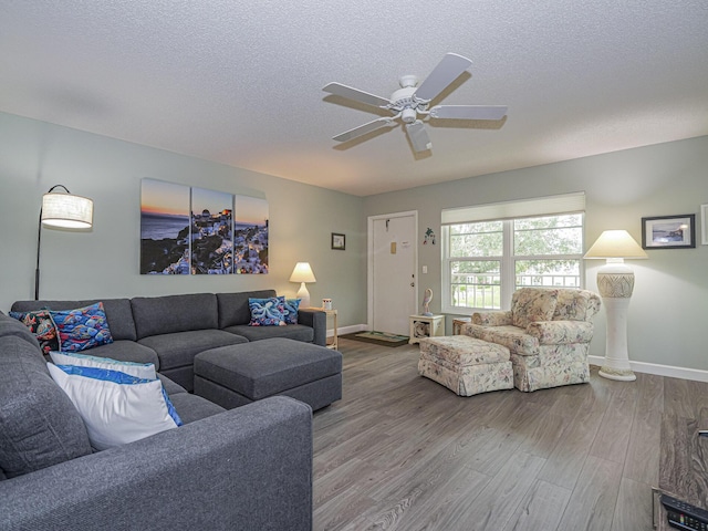 living room featuring ceiling fan, hardwood / wood-style flooring, and a textured ceiling