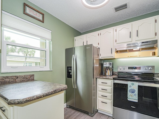 kitchen with appliances with stainless steel finishes, light hardwood / wood-style flooring, a textured ceiling, and white cabinets