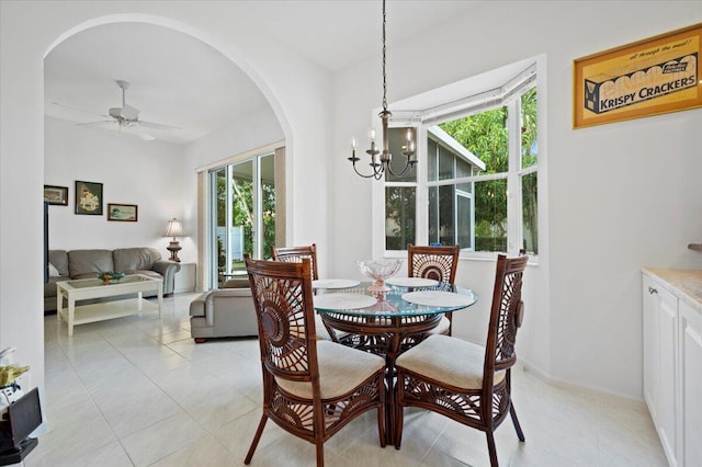 tiled dining room with ceiling fan with notable chandelier