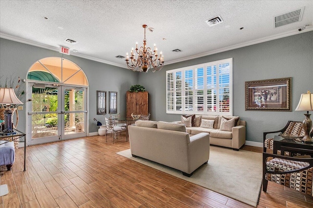 living room with a notable chandelier, crown molding, and a textured ceiling