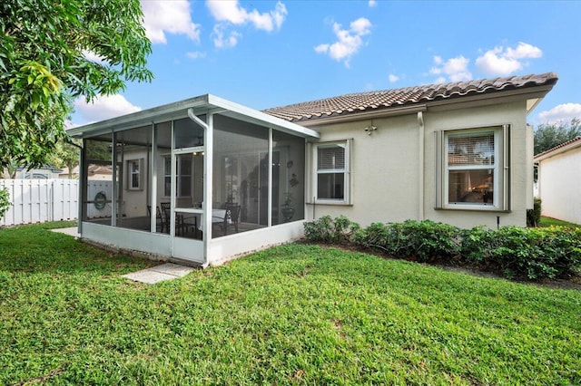 rear view of house with a sunroom and a yard