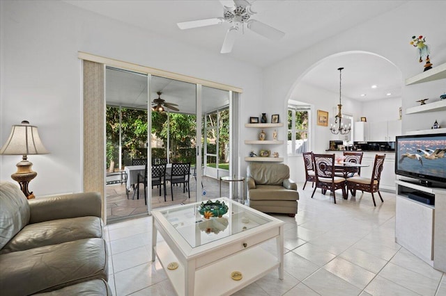 tiled living room with ceiling fan with notable chandelier